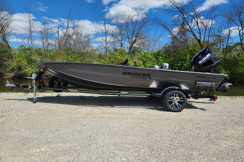 Slide: The Image of 2026 Smoker Craft Viper XR 175 Pro boat on trailer, parked near a riverbank. - 2