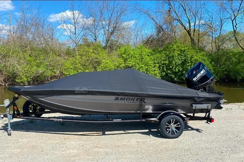 Slide: The Image of 2026 Smoker Craft Viper XR 175 Pro boat with cover, parked near a river. - 3
