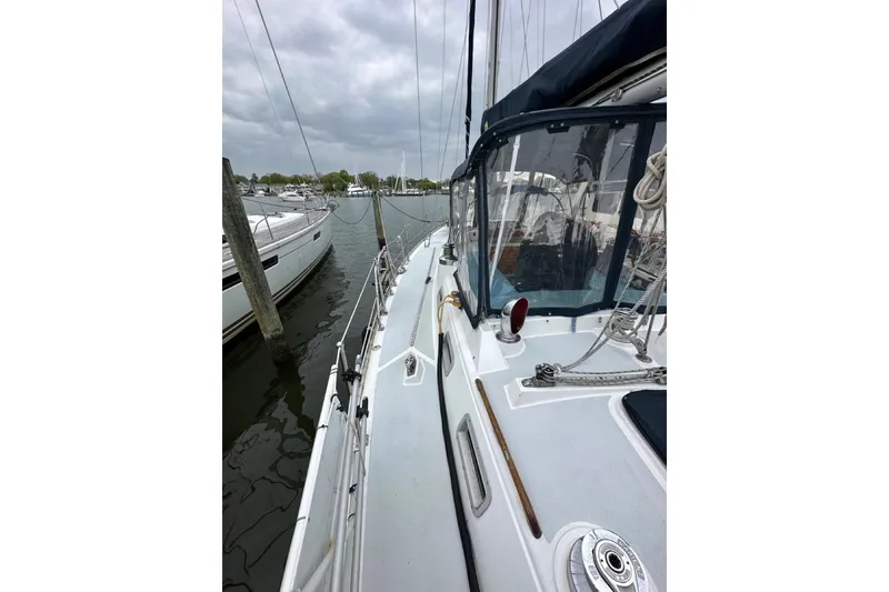 Slide: The Image of 1989 Hylas 44 sailboat docked, featuring deck and rigging under cloudy skies. - 32