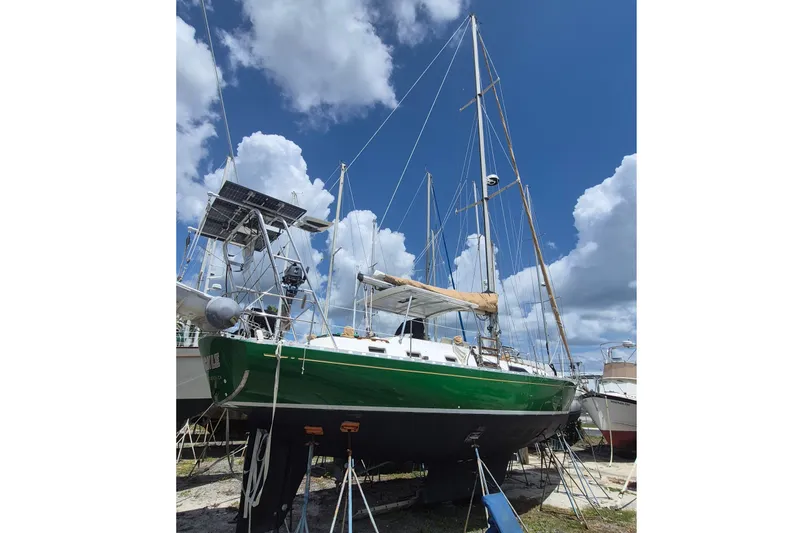 The Image of Sailboat Hylas 44, 1989 model, with green hull, docked under a cloudy sky. - 0