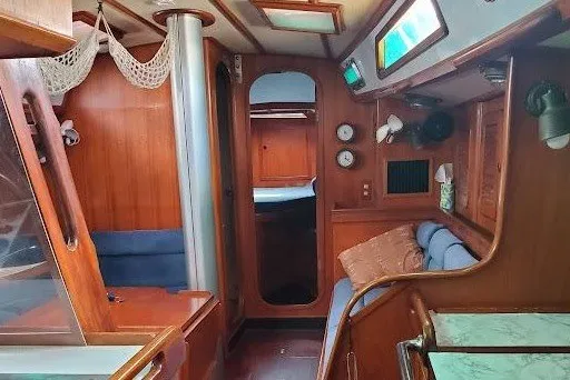Slide: The Image of Interior of a 1989 Hylas 44 yacht, featuring wooden cabinetry and cozy seating. - 9