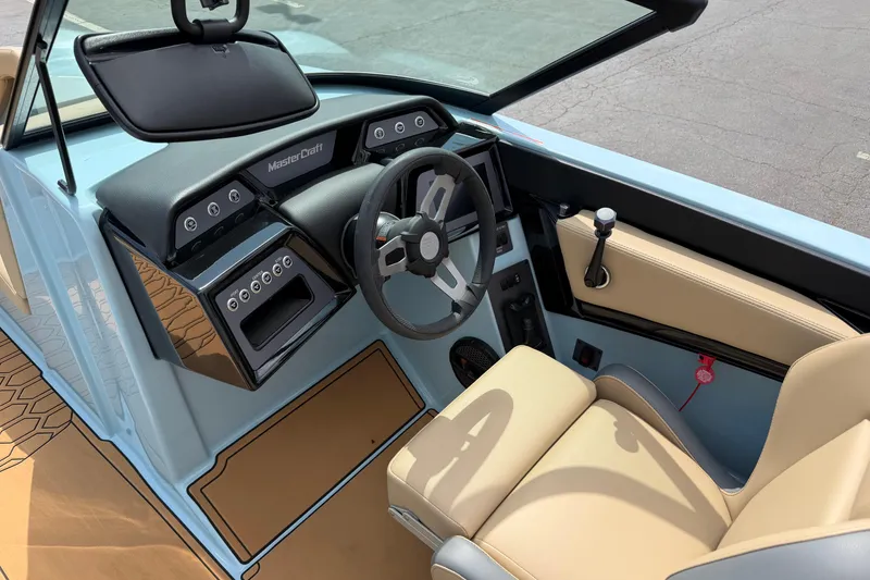 Slide: The Image of 2025 MasterCraft NXT22 boat interior with modern dashboard and beige seating. - 12