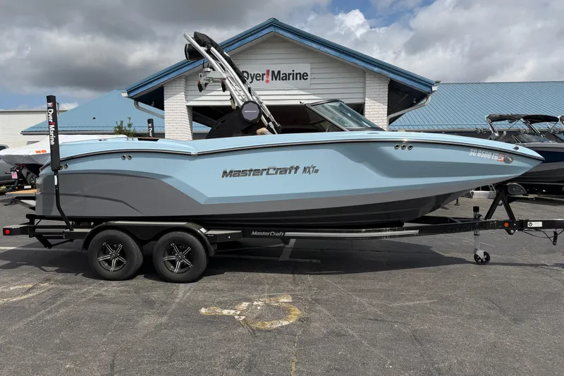 Slide: The Image of 2025 MasterCraft NXT22 boat on trailer at dealership, under cloudy sky. - 3