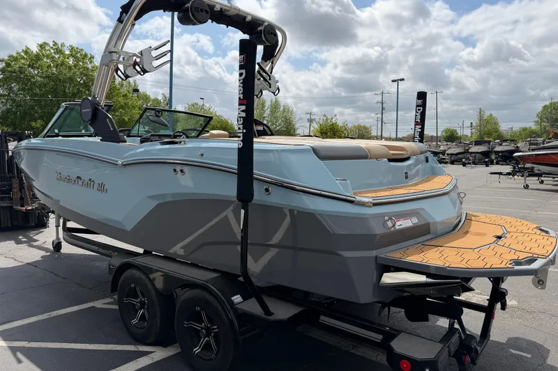Slide: The Image of 2025 MasterCraft NXT22 boat on trailer, parked outdoors under cloudy sky. - 4