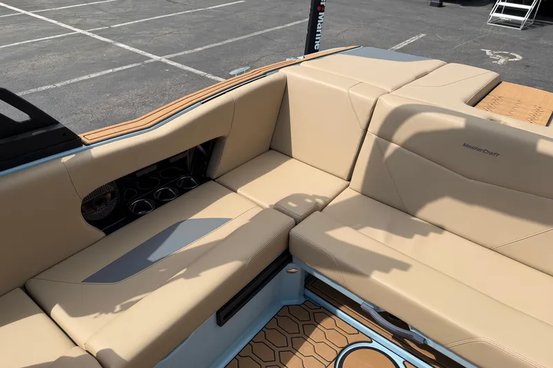 Slide: The Image of 2025 MasterCraft NXT22 boat interior with beige seating and cup holders. - 9
