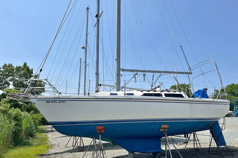 The Image of 1988 Catalina 30 MkII sailboat on stands, blue hull, clear sky background. - 0