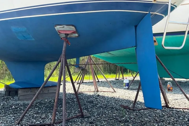 Slide: The Image of 1988 Catalina 30 MkII sailboat on stands, blue hull, gravel ground. - 2