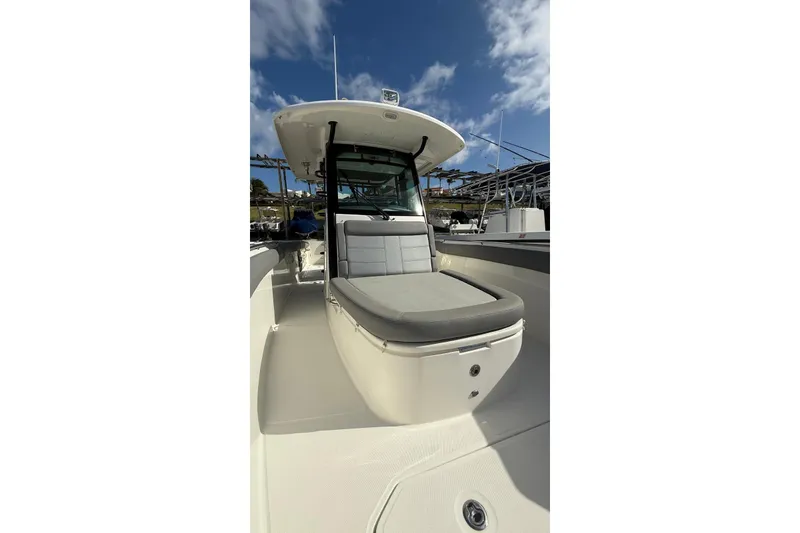 Slide: The Image of 2023 Boston Whaler 330 Outrage boat interior with cushioned seating under a clear sky. - 11