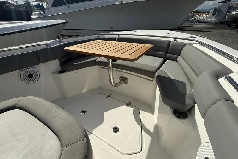 Slide: The Image of 2023 Boston Whaler 330 Outrage boat interior with seating and wooden table. - 12