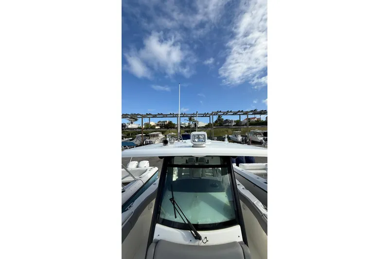 Slide: The Image of 2023 Boston Whaler 330 Outrage boat under a clear blue sky at a marina. - 14