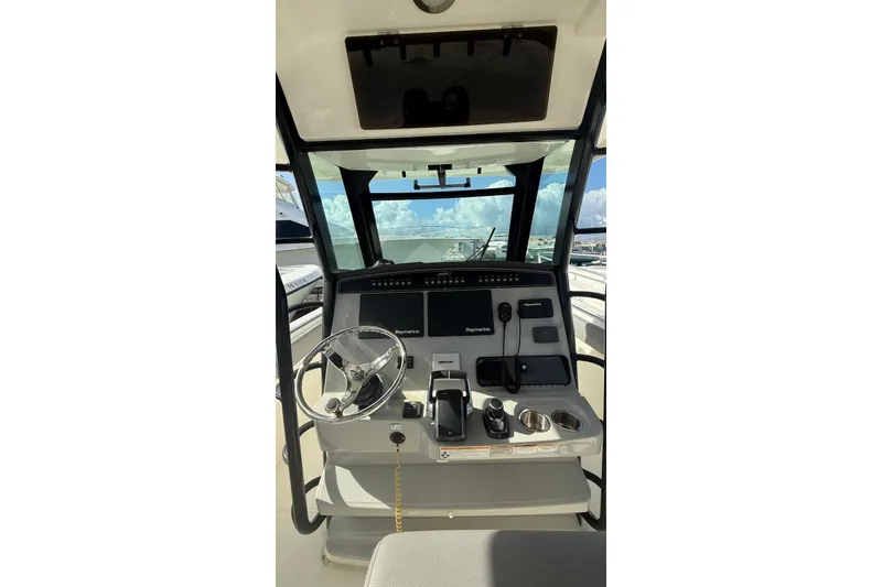 Slide: The Image of 2023 Boston Whaler 330 Outrage helm with steering wheel and navigation controls. - 6