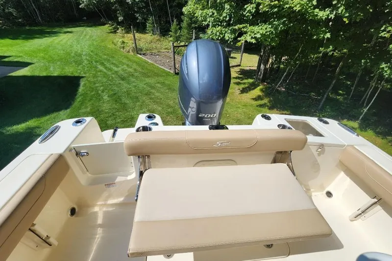 Slide: The Image of 2022 Scout 215 XSF boat with Yamaha 200 engine, beige seating, and lush green surroundings. - 4