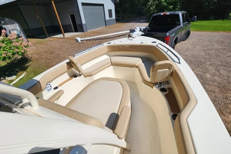 Slide: The Image of 2022 Scout 215 XSF boat interior with tan seating, parked near a truck. - 5