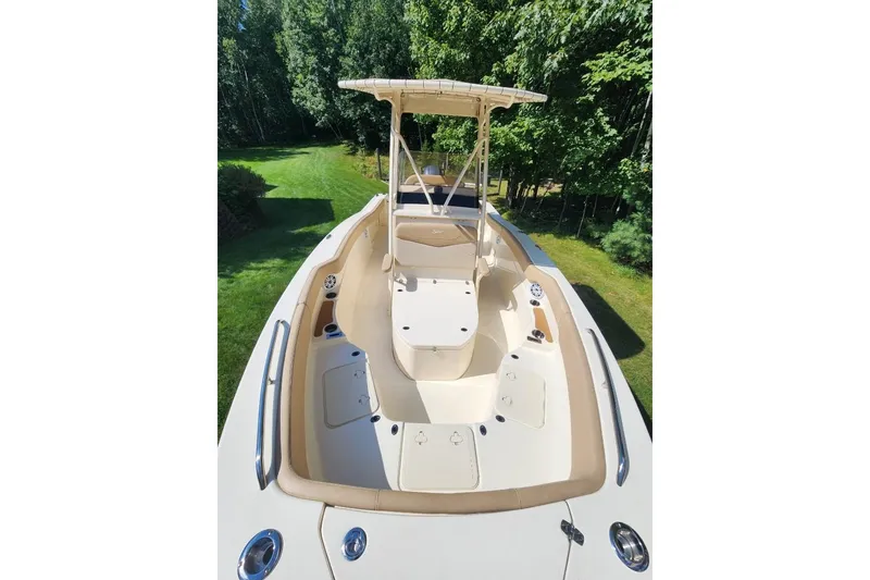 Slide: The Image of 2022 Scout 215 XSF boat with spacious deck, surrounded by lush greenery. - 7