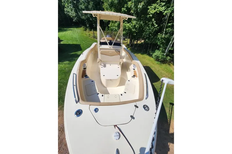 Slide: The Image of 2022 Scout 215 XSF boat with spacious deck and seating, surrounded by lush greenery. - 8