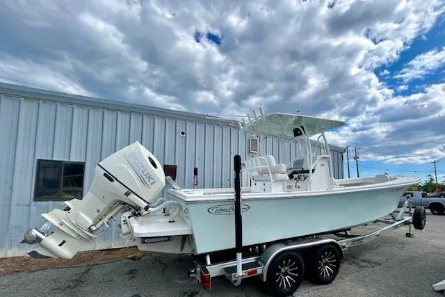 Slide: The Image of 2020 Pair Customs 24 Center Console MV boat on trailer, parked near metal building under cloudy sky. - 3