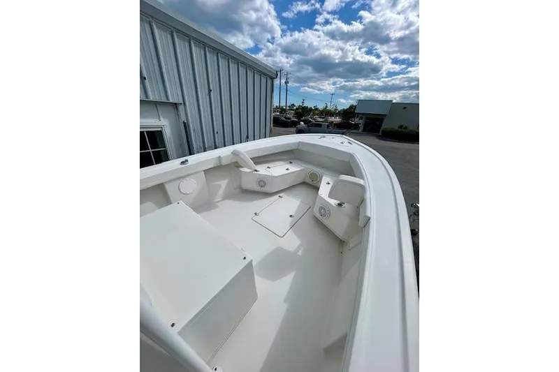 Slide: The Image of 2020 Pair Customs 24 Center Console MV boat, white interior, docked near metal building. - 6