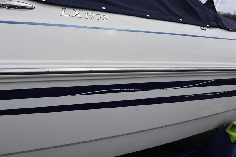 Slide: The Image of Side view of a 2018 Larson LX 195 I/O boat with blue stripes. - 18