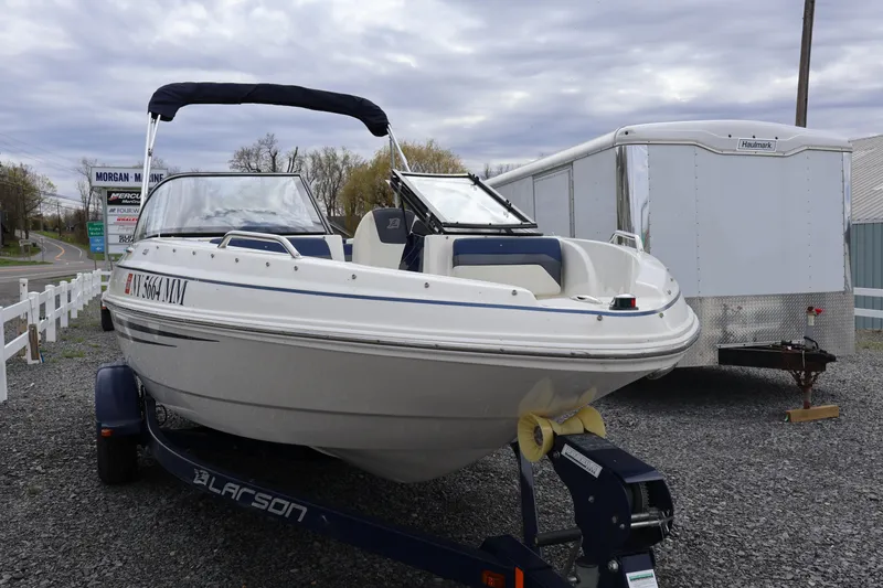 Slide: The Image of 2018 Larson LX 195 I/O boat on trailer, parked outdoors near a road. - 19
