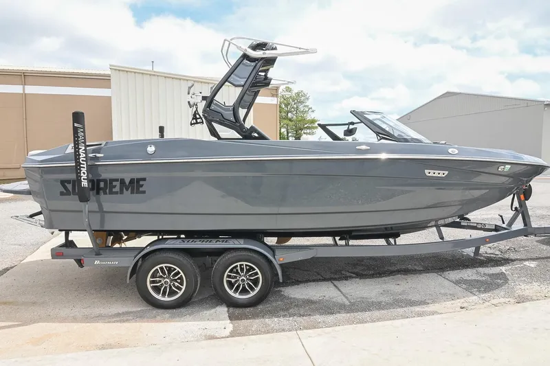 Slide: The Image of 2024 Supreme S220 boat on trailer, sleek gray design, parked outdoors. - 13