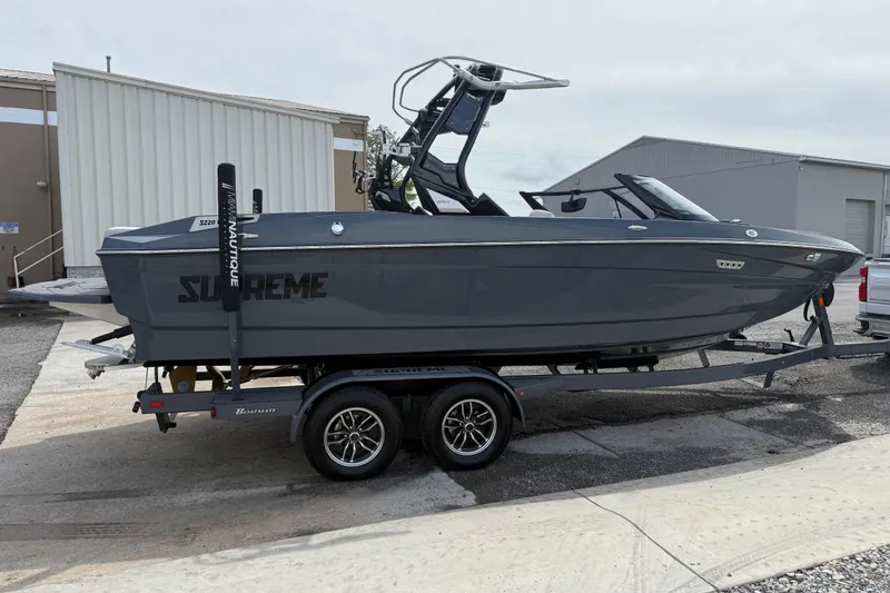Slide: The Image of 2024 Supreme S220 boat on trailer, sleek gray design, parked outdoors. - 7