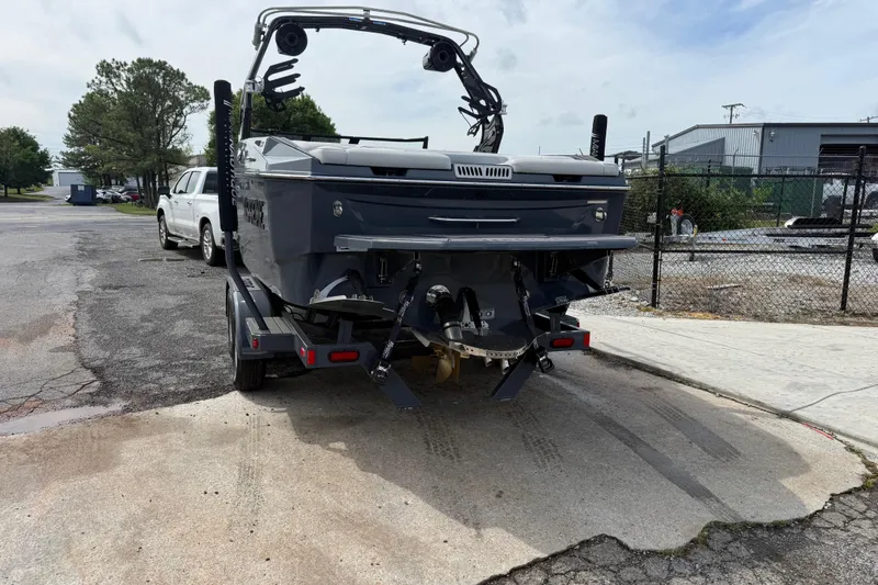 Slide: The Image of 2024 Supreme S220 boat on trailer, parked outdoors near industrial area. - 8