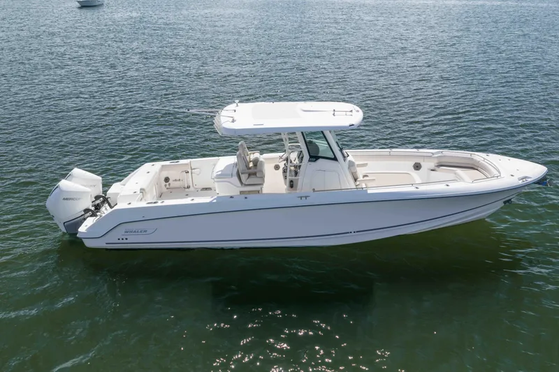 Slide: The Image of 2021 Boston Whaler 330 Outrage boat on calm water, showcasing sleek design and powerful engines. - 10