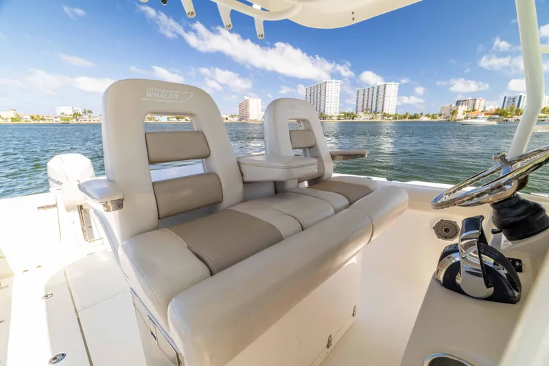 Slide: The Image of 2021 Boston Whaler 330 Outrage boat interior with luxurious seating and scenic waterfront view. - 27