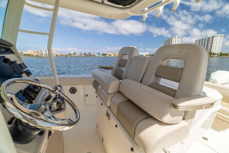 Slide: The Image of 2021 Boston Whaler 330 Outrage boat interior with luxurious seating and steering wheel. - 28