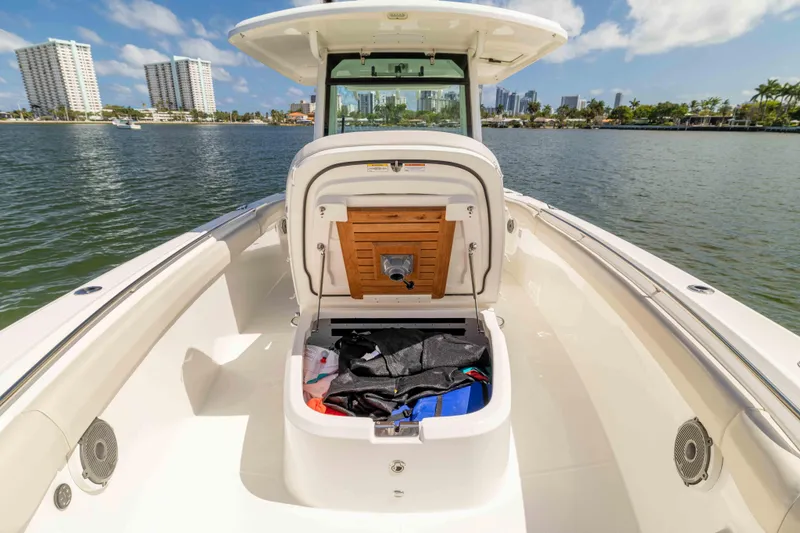 Slide: The Image of 2021 Boston Whaler 330 Outrage boat with open storage compartment, docked near city skyline. - 30