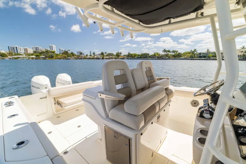 Slide: The Image of 2021 Boston Whaler 330 Outrage boat interior with dual seats and scenic waterfront view. - 32