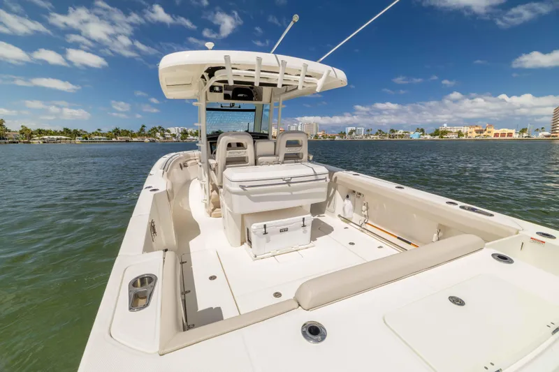 Slide: The Image of 2021 Boston Whaler 330 Outrage boat on calm water, showcasing spacious deck and seating. - 34