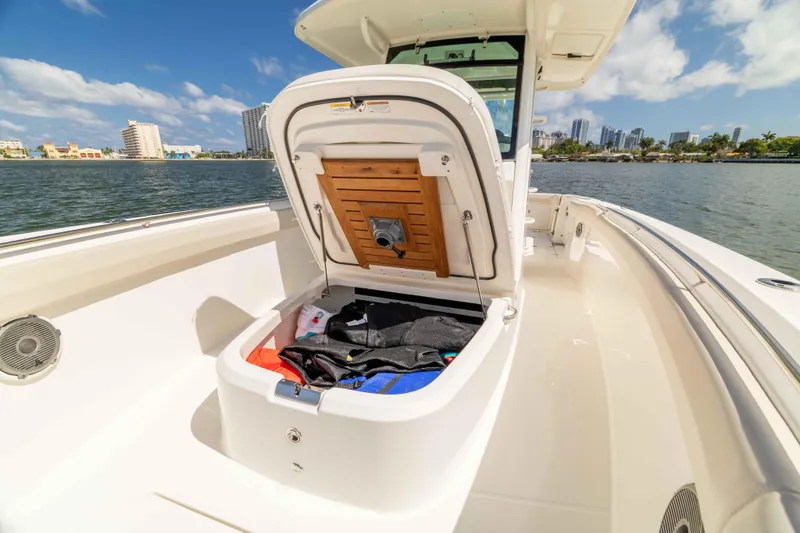 Slide: The Image of 2021 Boston Whaler 330 Outrage boat with open storage compartment, docked near city skyline. - 37