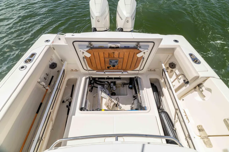 Slide: The Image of 2021 Boston Whaler 330 Outrage boat interior with open storage compartments and twin engines. - 44