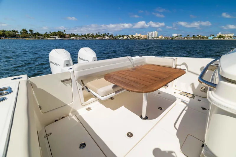Slide: The Image of 2021 Boston Whaler 330 Outrage boat deck with wooden table and Mercury engines. - 45