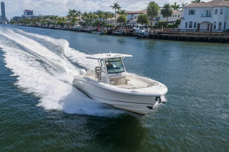 Slide: The Image of 2021 Boston Whaler 330 Outrage cruising on a scenic waterway with waterfront homes. - 5