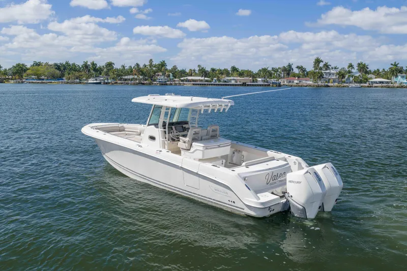 Slide: The Image of 2021 Boston Whaler 330 Outrage boat on calm water, with scenic shoreline background. - 8