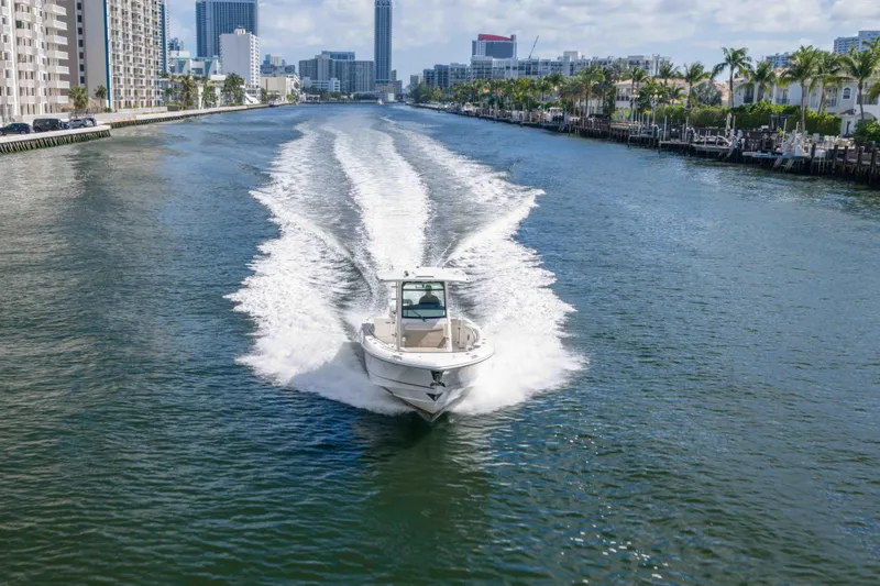 Slide: The Image of 2021 Boston Whaler 330 Outrage cruising on a scenic urban waterway. - 9