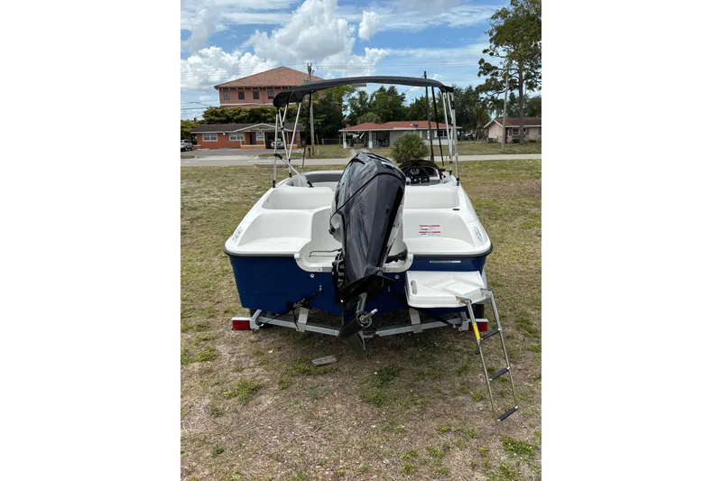 Slide: The Image of 2026 Bayliner Element E16 boat with outboard motor and ladder, parked on grass. - 10