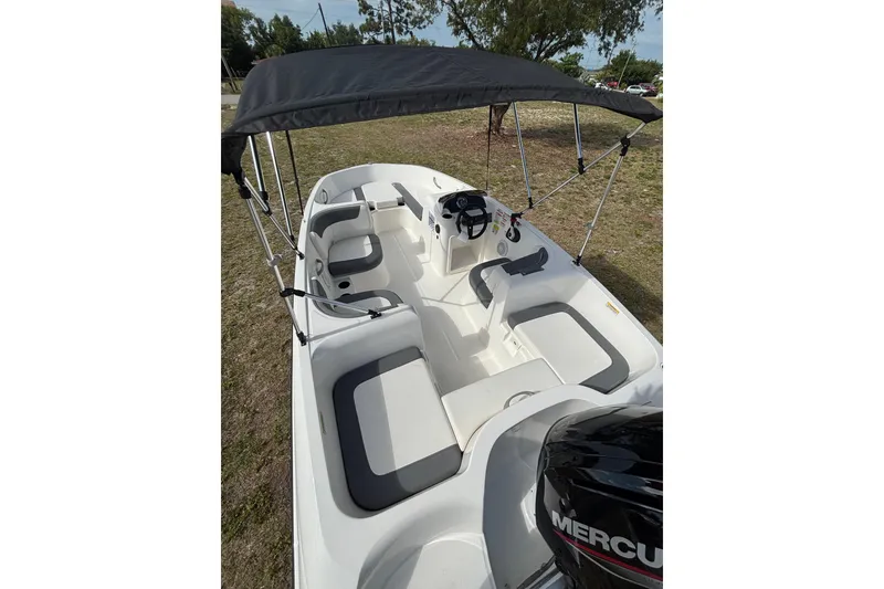 Slide: The Image of 2026 Bayliner Element E16 boat with canopy and seating, parked on grass. - 13
