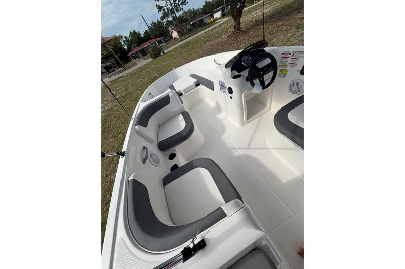 Slide: The Image of 2026 Bayliner Element E16 boat interior with seating and steering wheel, parked on grass. - 15