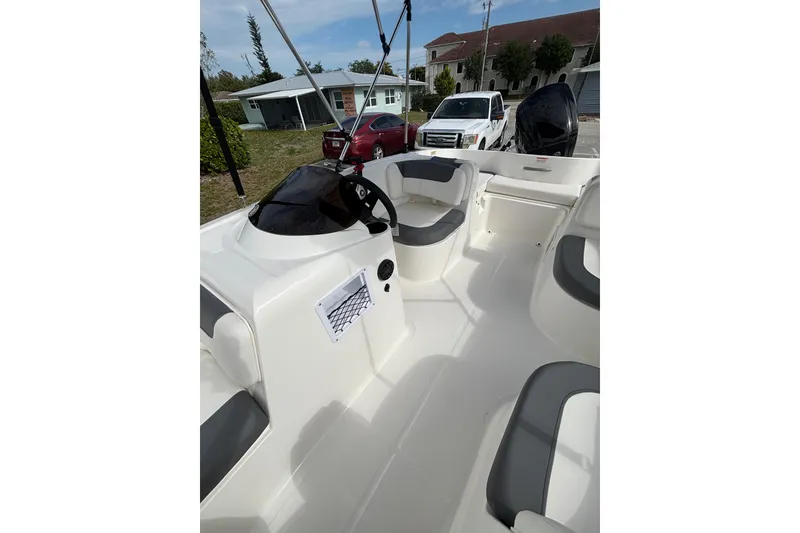 Slide: The Image of 2026 Bayliner Element E16 boat interior with seating and steering wheel, parked outdoors. - 17