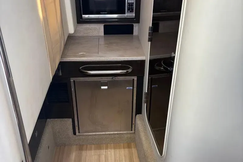 Slide: The Image of 2015 Formula 350 Crossover Bowrider interior with kitchenette, microwave, and compact fridge. - 33