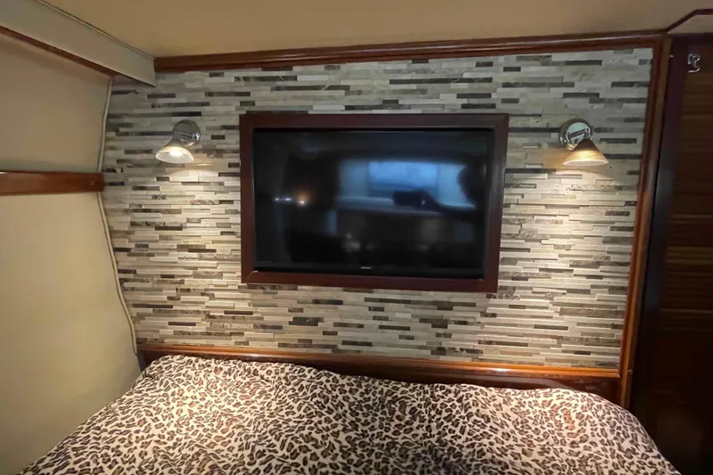 Slide: The Image of 1989 Sea Ray 380 Aft Cabin interior with TV, stone wall, and leopard print bedding. - 10