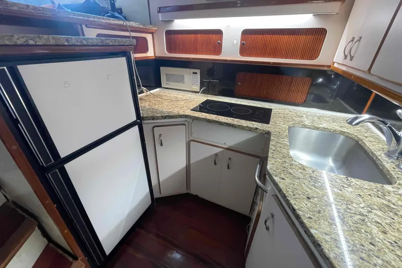 Slide: The Image of 1989 Sea Ray 380 Aft Cabin kitchen with granite countertops, stove, sink, and refrigerator. - 3