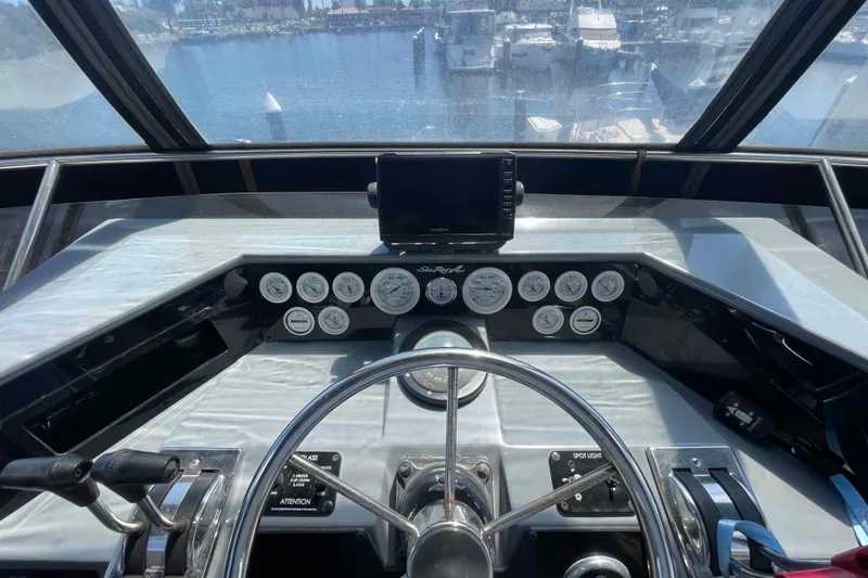 Slide: The Image of 1989 Sea Ray 380 Aft Cabin helm with gauges and steering wheel, overlooking marina. - 36