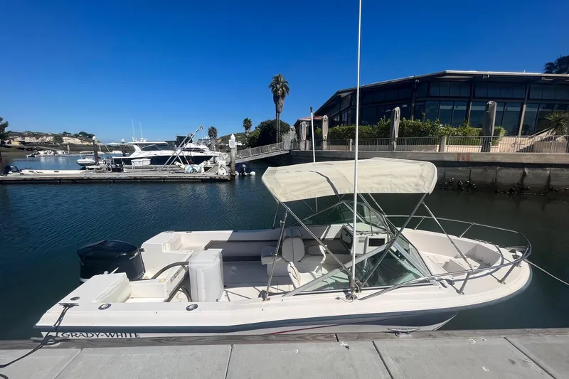 The Image of 1986 Grady-White Tournament 190 boat docked in a marina under clear blue sky. - 1