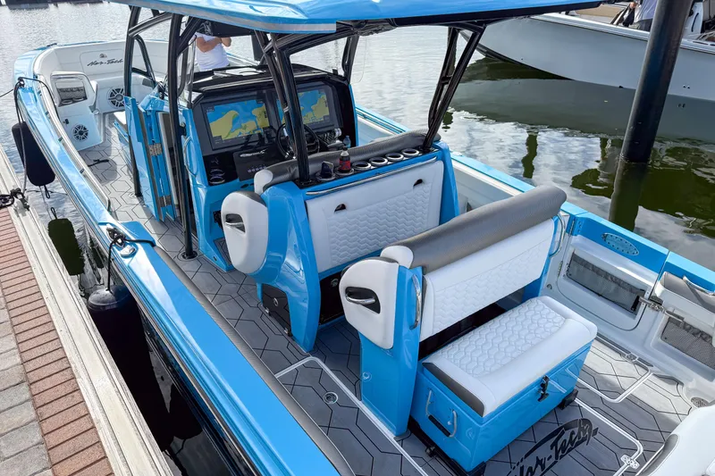 Slide: The Image of 2025 Nor-Tech 390 Sport Center Console boat with blue and white interior at a dock. - 6