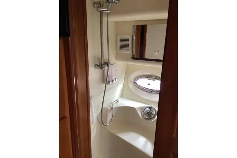 Slide: The Image of 2006 Silverton 38 Sport Bridge cabin interior with bed, wooden accents, and porthole window. - 28