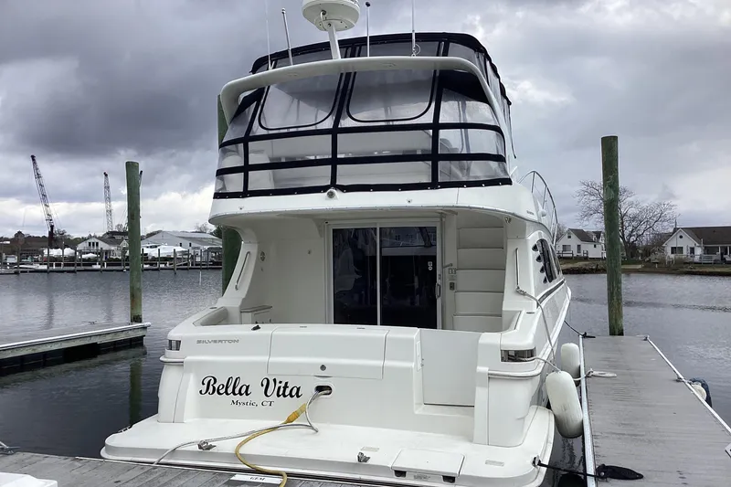 Slide: The Image of 2006 Silverton 38 Sport Bridge yacht docked, featuring sleek design and spacious upper deck. - 4